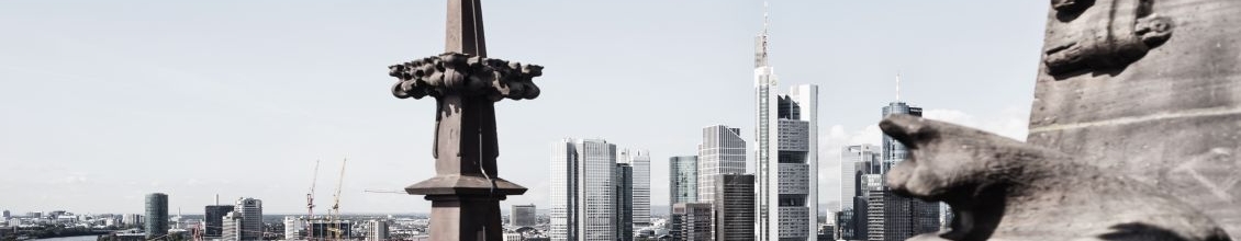 Bild einer Stadt, rechts eine Statur, links ein Fluss