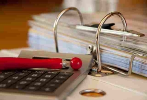 Bild von Ordner, Taschenrechner und rotem Kugelschreiber