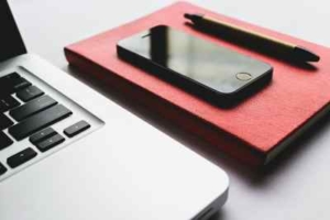 Bild von einem Laptop, Handy, Heft und Stift