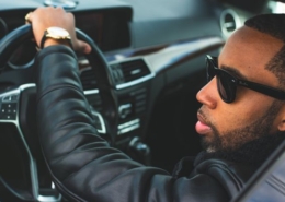 Mann sitzt mit Sonnenbrille am Lenkrad