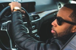 Mann sitzt mit Sonnenbrille am Lenkrad