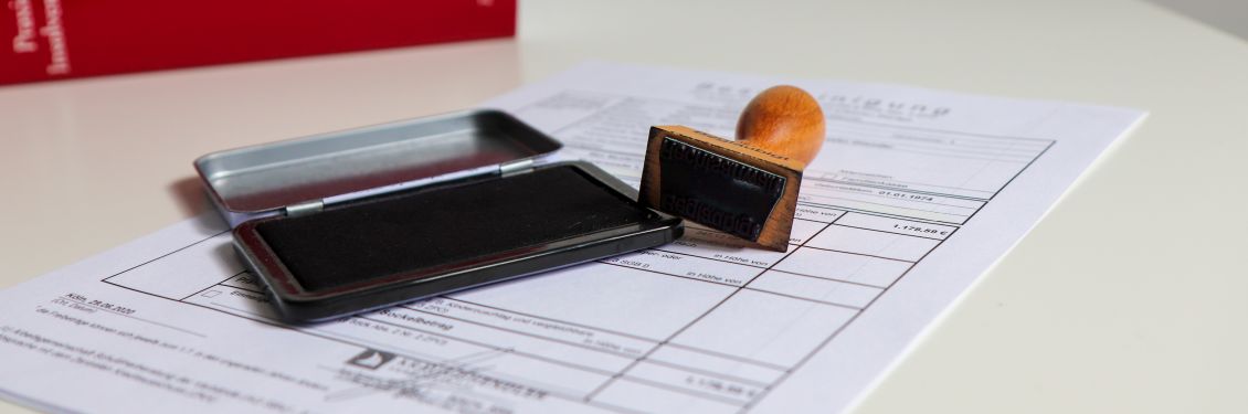 KGR_Insolvenzrecht_Slider2_1130x375 Das Bild zeigt ein Dokument und einen Stempel