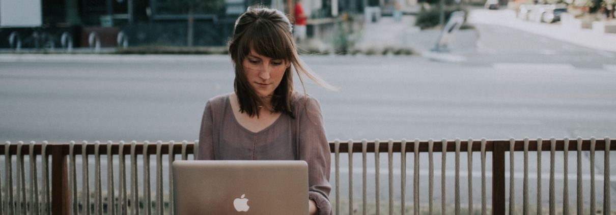 Bild von einer Frau am Tisch draußen mit Laptop