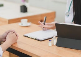 Ärztin füllt im Gespräch mit Patient Dokument aus