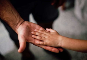 Zwei ineinander liegende Hände von Kind und Erwachsenem