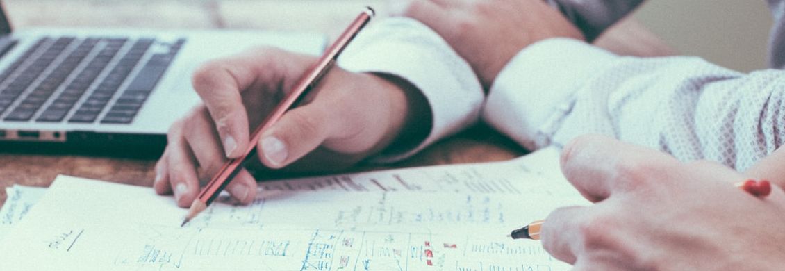 Beratungsgespräch zum GKV-Wechsel Zwei Hände, die Stifte halten und Notizen auf Zetteln machen